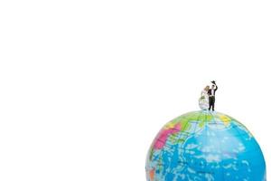 Miniaturhochzeits-, Braut- und Bräutigampaar auf einem Globus auf einem weißen Hintergrund foto