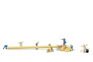 Miniaturarbeiter, die einen Bleistift auf einem weißen Hintergrund spitzen foto