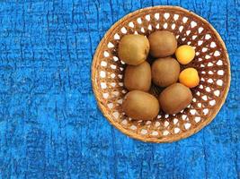Kiwis und Aprikosen in einem Weidenkorb auf einem hölzernen Tischhintergrund foto
