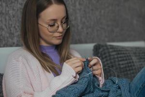 jung schön Frau strickt ein Wolle Sweatshirt mit ihr besitzen Hände. ein Frau strickt von dick Garn. handgemacht Kleidung. das Mädchen ist beschäftigt, verlobt im ihr Hobbys. foto