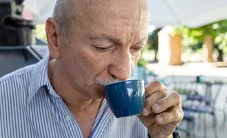 Alten Mann Trinken Espresso Kaffee beim ein draussen Cafe foto