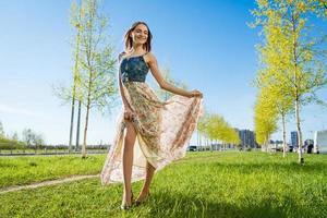 Porträt glücklich schön jung Frau entspannend im Park im lange Kleid. froh foto