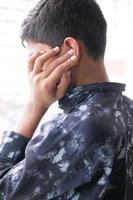Teenager mit Ohrenschmerzen, die sein schmerzendes Ohr berühren, foto
