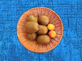 Kiwis und Aprikosen in einem Weidenkorb auf einem hölzernen Tischhintergrund foto