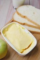 frische Butter in einem Behälter mit Brot auf weißem Hintergrund foto