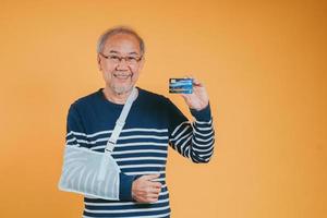 Arm gebrochen. Senior männlich Schlinge Unterstützung Hand zuversichtlich Lächeln gebrochen nach Unfall tragen Arm Schiene zum Behandlung Show gut unterzeichnen. Gesundheit Versicherung auf Handy, Mobiltelefon Konzept. foto