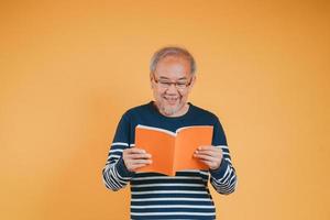 glücklich positiv Senior männlich lächelnd und lesen Buch Bildung Wissen Lernen auf Farbe Hintergrund. foto