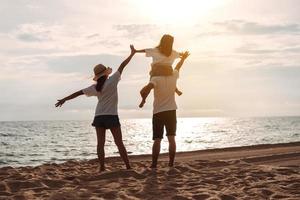 glücklich asiatisch Familie genießen das Meer Strand beim bestehend aus Vater, Mutter und Tochter haben Spaß spielen Strand im Sommer- Ferien auf das Ozean Strand. glücklich Familie mit Urlaube Zeit Lebensstil Konzept. foto