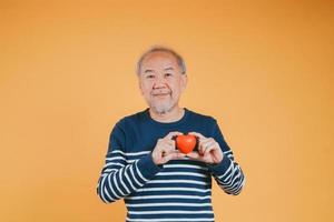 Senior männlich halten Herz Liebe Emotion Versicherung Konzept auf Farbe Hintergrund. foto