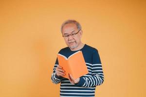 glücklich positiv Senior männlich lächelnd und lesen Buch Bildung Wissen Lernen auf Farbe Hintergrund. foto