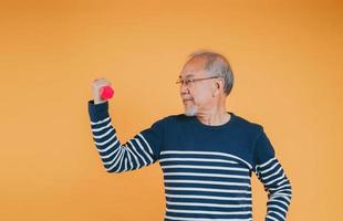 Senior männlich mit Hantel zum Übung aktiv Lebensstil im Pensionierung Leben Gesundheit Pflege auf Farbe Hintergrund. foto