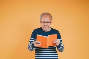 glücklich positiv Senior männlich lächelnd und lesen Buch Bildung Wissen Lernen auf Farbe Hintergrund. foto