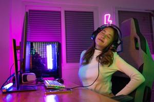 jung Menschen Rückenschmerzen. Spieler und E-Sport online von asiatisch Frau spielen online Computer Video Spiel mit Beleuchtung Wirkung, Übertragung Streaming Leben beim heim. sie ein Rückenschmerzen fällig zu Sitzung zum ein lange Zeit foto