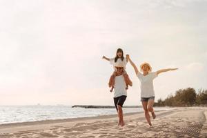 glücklich asiatisch Familie genießen das Meer Strand beim bestehend aus Vater, Mutter und Tochter haben Spaß spielen Strand im Sommer- Ferien auf das Ozean Strand. glücklich Familie mit Urlaube Zeit Lebensstil Konzept. foto