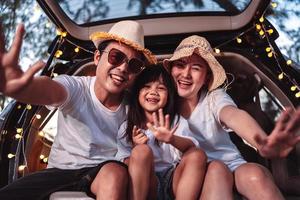 glücklich Familie mit Auto Reise und Camping Straße Reise. Sommer- Ferien im Auto im das Sonnenuntergang, Papa, Mama und Tochter glücklich Reisen genießen zusammen Fahren im Feiertage, Menschen Lebensstil Reiten durch Automobil. foto