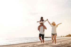 glücklich asiatisch Familie genießen das Meer Strand beim bestehend aus Vater, Mutter und Tochter haben Spaß spielen Strand im Sommer- Ferien auf das Ozean Strand. glücklich Familie mit Urlaube Zeit Lebensstil Konzept. foto