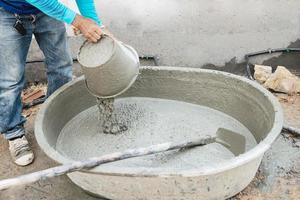 Baumeister Auftragnehmer Mann Job mischen Beton im Industrie Arbeit Projekt, Gießen nass Flüssigkeit Material in das groß Mischen Tablett im Konstruktion Seite? ˅ wie Fachmann Beschäftigung foto