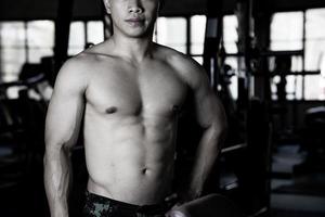 sexy Körper von muskulös jung Soldat asiatisch Mann im Fitnessstudio. Konzept von Gesundheit Pflege, Übung Fitness, stark Muskel Masse, Körper Erweiterung, Fett die Ermäßigung zum Herren Gesundheit Ergänzung Produkt Präsentation. foto