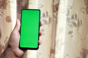 Mann hält Smartphone mit grünem Bildschirm
