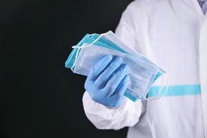 medizinischer Handschuh, der schützende chirurgische Gesichtsmasken hält