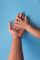 Vater hält Babys Hand auf blauem Hintergrund foto