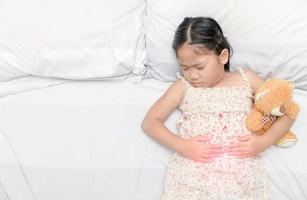 asiatisch Mädchen Leiden von Magenschmerzen foto