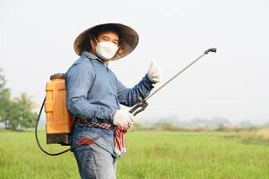 asiatisch Farmer ist Sprühen organisch Dünger beim Paddy Feld. Daumen hoch. Konzept mit freundlich Produkt mit Umgebung Landwirtschaft mit Nein Chemikalien verwenden. Sicherheit mit Benutzer und Umfeld. foto