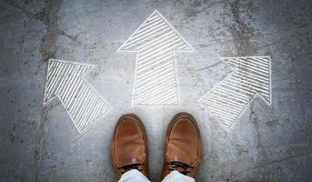 braun Leder Schuhe und drei geometrisch kalkhaltig Pfeile auf Asphalt - - Wahl Konzept foto