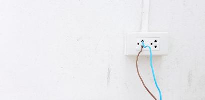 nackt Blau und braun Draht Installieren und Stecker im zu elektrisch Auslauf Box auf Weiß Zement Mauer mit Pipeline und Kopieren Raum. unsicher Installation, Sicherheit, Achtung und nicht Standard, kurz Schaltkreis Konzept foto