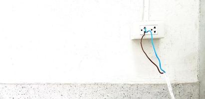nackt Blau und braun Draht Installieren und Stecker im zu elektrisch Auslauf Box auf Weiß Zement Mauer mit Pipeline und Kopieren Raum. unsicher Installation, Sicherheit, Achtung und nicht Standard, kurz Schaltkreis Konzept foto