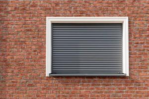 ein Backstein Mauer mit Fenster und geschlossen Fensterläden foto