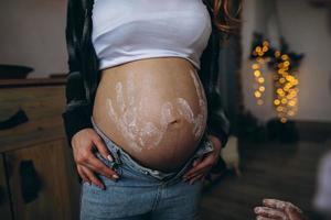 Frau schwanger Bauch mit Kind druckt im Hemd und Blau Jeans foto