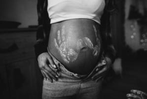 Frau schwanger Bauch mit Kind druckt im Hemd und Blau Jeans foto