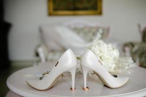 weiblich Füße im Weiß Hochzeit Sandalen mit ein Strauß von Kamille foto