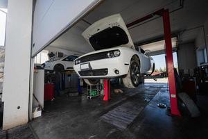 Muscle-Car mit offener Motorhaube an der Service-Reparaturstation im Aufzug. foto