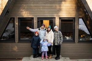 Familie mit drei Kinder gegen hölzern Kabine winzig Haus. Kinder im Landschaft. foto