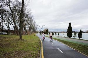 zwei Mädchen Radfahren auf Zyklus Pfad entlang das Stadt Gasse. foto