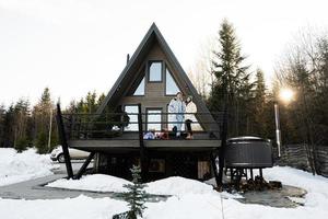 Familie mit zwei Töchter auf Terrasse aus Gitter winzig Haus im das Berge. foto