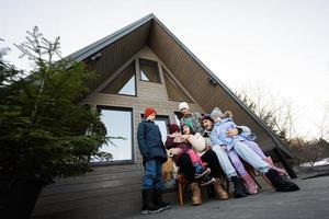 groß Familie mit vier Kinder sitzen auf Terrasse aus Gitter winzig Haus im das Berge. foto