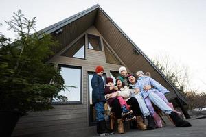 groß Familie mit vier Kinder sitzen auf Terrasse aus Gitter winzig Haus im das Berge. foto