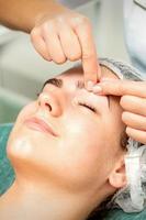 Kosmetikerin machen Massage auf Augenbraue foto