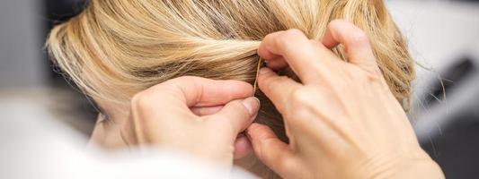 Friseur sticht Haar mit Haarnadel foto