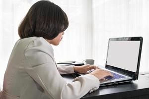 junge Frau in eleganter Freizeitkleidung, die am Laptop arbeitet foto