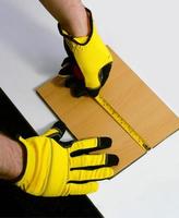 ein Mann im Arbeit Handschuhe werden messen ein hölzern Block mit ein Band messen foto