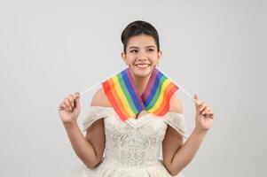 junge asiatische schöne Braut mit Regenbogenfahne auf weißem Hintergrund foto