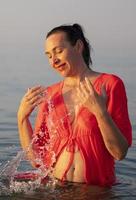 schön Alten Frau badet im das Meer und spritzt Wasser. foto