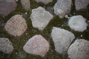 Hintergrund von ein alt Mauer gemacht von Rau groß Steine, Felsbrocken und Moos. foto