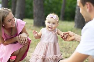 Ehemann, Ehefrau und ihr wenig Tochter zum ein gehen im das Park. glücklich Papa und Mama mit einer Jahr alt Baby Mädchen. jung Familie. foto