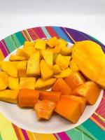 Scheiben von Mango und Papaya Obst auf ein bunt Motiv Teller foto