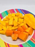 Scheiben von Mango und Papaya Obst auf ein bunt Motiv Teller foto